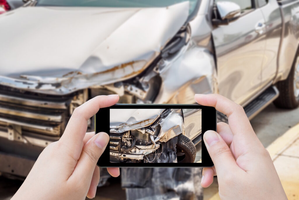 woman using mobile smartphone taking photo of car accident damaged for insurance
